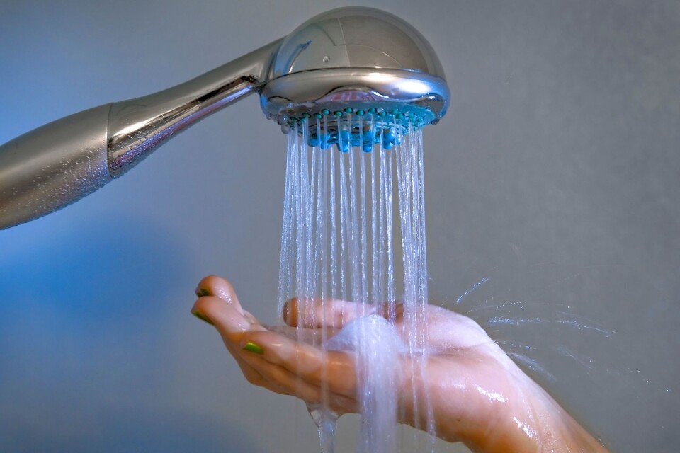 Rinnande vatten från en dusch som en hand fångar upp vattnet