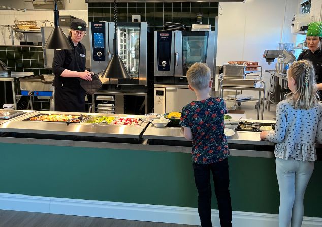 två barn som plockar mat i matsalen