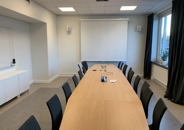 konferensrum med ett furubord och grå stolar
