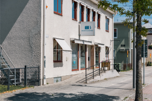 En bild på ett grått hus med en Boxholmshus logga på och en väg utanför